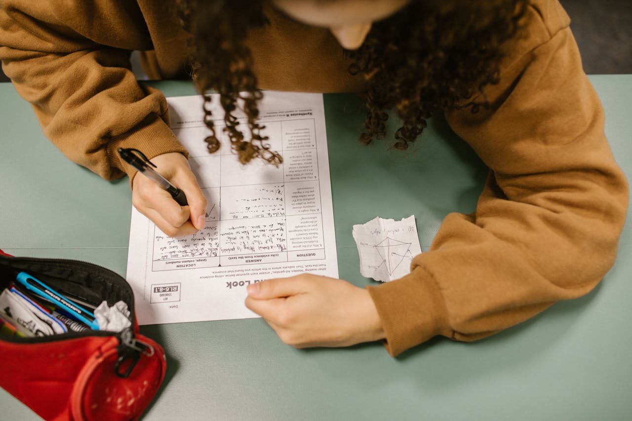 creative-03 Overhead view of a student writing an exam with a cheat sheet on the desk.